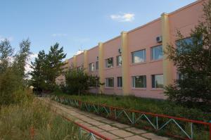 a row of pink and yellow buildings next to a sidewalk at Sanatoriy Zhosaly in Qarqaraly