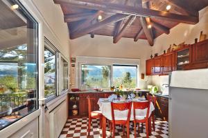 una cucina con tavolo, sedie rosse e finestre di Anemelia' Villa ad Áyios Dhimítrios