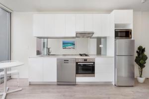 a kitchen with white cabinets and stainless steel appliances at Bondi Beach Studio King Suite + Balcony in Sydney