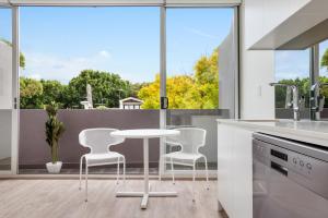kuchnia z białym stołem i krzesłami przed oknem w obiekcie Bondi Beach Studio King Suite + Balcony w mieście Sydney