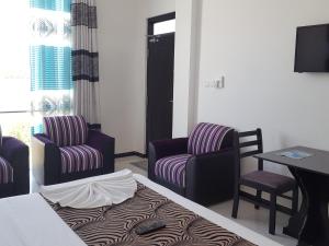 a hotel room with a bed and two chairs and a table at Trinco Lagoon in Trincomalee
