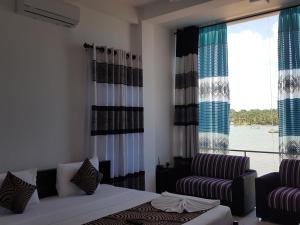 a bedroom with a bed and a couch and a window at Trinco Lagoon in Trincomalee