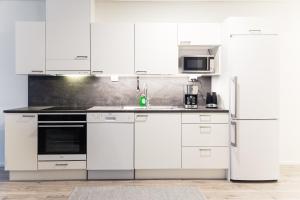 een keuken met witte kasten en een koelkast bij Kylväjänkuja Apartments in Vantaa