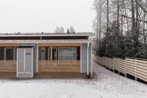 een houten huis met een hek in de sneeuw bij Kylväjänkuja Apartments in Vantaa
