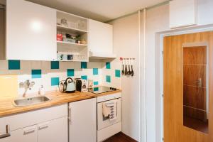 eine Küche mit weißen Schränken und blauen und weißen Fliesen in der Unterkunft MOOKI Beach Apartment in Bodensdorf