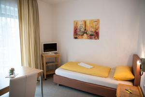 Habitación de hotel con cama y TV en Hotel Garni Trumm en Dillingen an der Donau