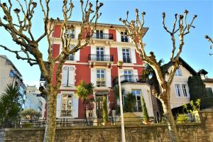 a red building with trees in front of it at Hôtel & Espace Bien-être La Maison du Lierre in Biarritz