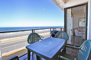 a table and chairs on a balcony with a view of the ocean at Cap Du Mont Cape Town in Bloubergstrand