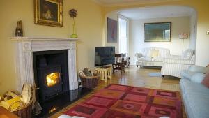 a living room with a fireplace and a couch at Greenden Farmhouse in Brechin