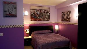 - une chambre avec des murs violets, un lit et deux affiches dans l'établissement Aparthotel Résidence Bara Midi, à Bruxelles