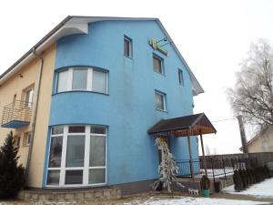 a blue building with snow on the ground at Penzión Lindava in Budmerice