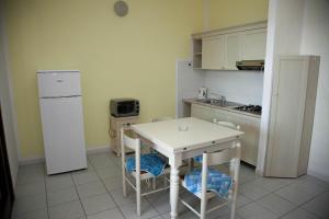 una cucina con frigorifero bianco, tavolo e sedie di A.I.R. Isola Rossa Borgo di Mare a Isola Rossa