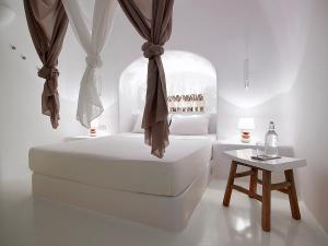 a white bedroom with a bed and a table at Blue Canaves Boutique Villa in Oia