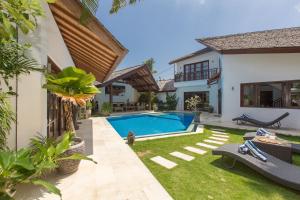 a backyard with a swimming pool and a house at Villa Origami by Nagisa Bali in Seminyak