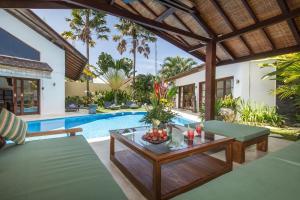 an outdoor patio with a table and a pool at Villa Origami by Nagisa Bali in Seminyak