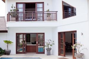 uma casa branca com portas de vidro e uma varanda em Villa Origami by Nagisa Bali em Seminyak