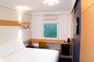 a room with a bed and a desk and a window at ibis Budget - Gosford in Gosford