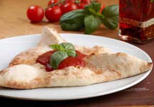 a piece of pizza on a white plate with tomato sauce at Hotel Sachsenklemme in Fortezza