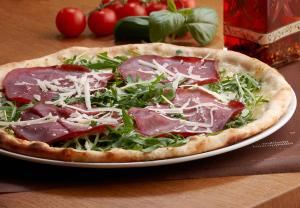 a pizza sitting on a plate on a table at Hotel Sachsenklemme in Fortezza