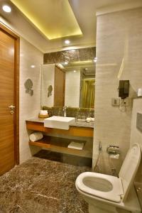 a bathroom with a toilet and a sink and a mirror at Park Ascent in Noida