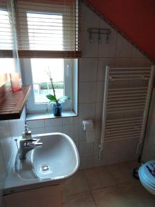 een badkamer met een witte wastafel en een raam bij Apartmán Pod lesem in Lipova Lazne