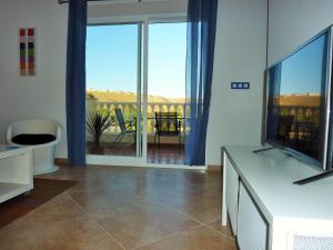 a living room with a television and a balcony at Vista Mazarron in Puerto de Mazarrón