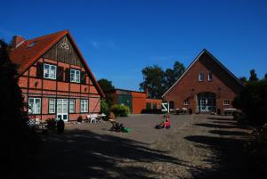 dos grandes edificios de ladrillo con niños sentados frente a ellos en Ferienhof Blunck en Wangels