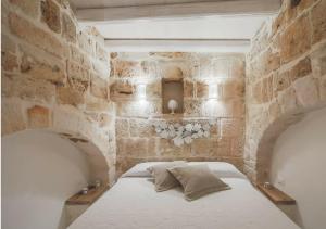 ein Schlafzimmer mit einem Bett in einer Steinmauer in der Unterkunft La dimora dei nonni in Monopoli