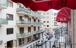 un balcone di un edificio con ombrellone rosso di Oberdan a Catania