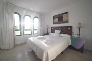 a bedroom with a large white bed and two windows at Hotel Apartamentos Manilva Sun in Manilva +115 photos