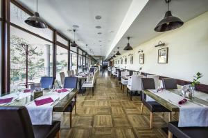 un comedor con mesas, sillas y ventanas en Crocus Apartments 310, 507, en Štrbské Pleso