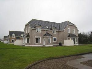 a large house in a yard with a green lawn at Moore Bay Holiday Homes in Kilkee