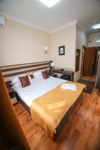 1 dormitorio con 1 cama grande y suelo de madera en Infinity Plaza Hotel, en Atyraū