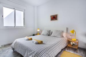 a white bedroom with a large bed with two pillows at Encantador Ático con Terraza in Seville