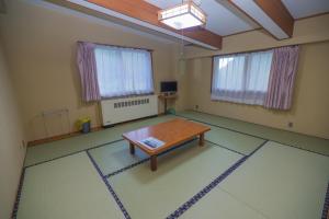 um quarto vazio com uma mesa e janelas em Aspen Shiga em Yamanouchi