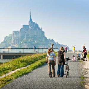 a group of people walking down a road with a bike at Les Colombes de la Baie du Mont Saint-Michel in Aucey-la-Plaine