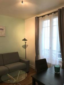 uma sala de estar com um sofá, uma mesa e uma janela em My Trip in Paris - Turgot em Paris