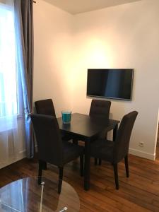 a dining room table with chairs and a flat screen tv at My Trip in Paris - Turgot in Paris