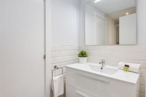 een witte badkamer met een wastafel en een spiegel bij Flateli Girona City Center 2 in Girona