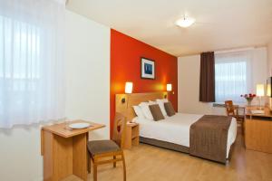 a hotel room with a bed and a table and a desk at Séjours & Affaires Rouen Normandie in Rouen