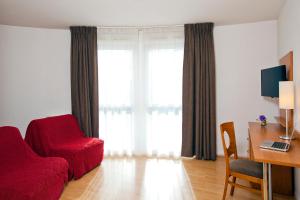 sala de estar con silla roja y escritorio en Séjours & Affaires Rouen Normandie en Ruan