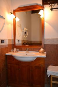 baño con lavabo y espejo grande en Masseria Protomastro Hotel en Gravina in Puglia