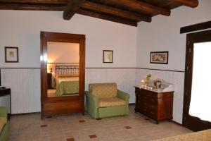 una camera da letto con specchio, sedia e cassettiera di Masseria Protomastro Hotel a Gravina in Puglia