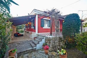una casa roja con macetas delante de ella en Anemelia' Villa en Áyios Dhimítrios