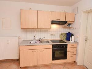 una cocina con armarios de madera y fregadero en Ferienwohnung-8-3 en Baabe