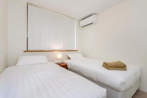 パースにあるCity Gardensの白い壁の部屋にベッドが2つある