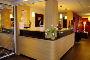a lobby with a counter with flowers in a vase at Kyriad Quimper Sud in Quimper