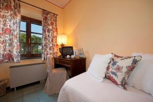 una camera con letto e scrivania con TV di Hotel Molino D'Era a Volterra