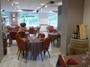 jadalnia ze stołami, krzesłami i beczkami z winem w obiekcie Hôtel Restaurant Prunières w mieście Aumont-Aubrac