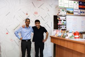 two men standing next to a counter in a store at Envoy Hostel & Tours in Yerevan